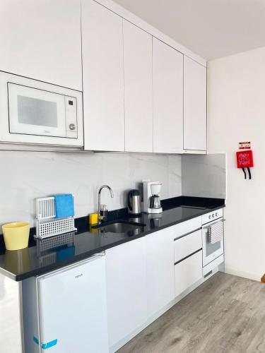 a white kitchen with a sink and a microwave at Apartamento T0 - MedSal Residence in Prainha