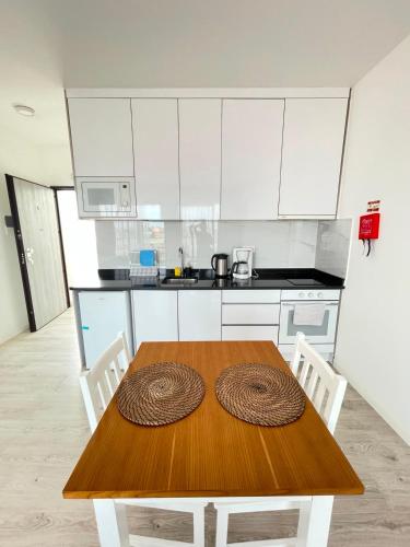 a kitchen with a wooden table and white cabinets at Apartamento T0 - MedSal Residence in Prainha