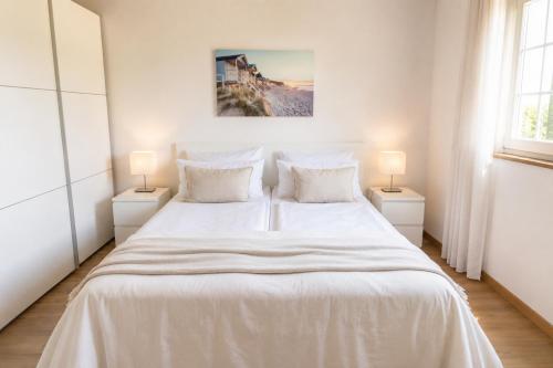 a bedroom with a large white bed with two lamps at Idyllische Wohnung mit Weitblick in Neukirchen-Vluyn