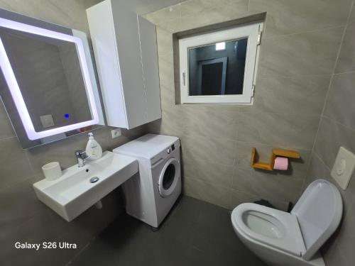 a bathroom with a sink and a washing machine at Vila HOXHA in Hamallë