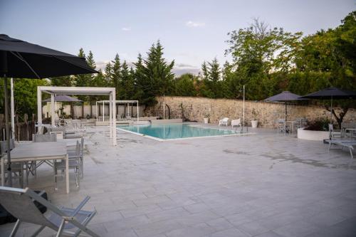 a swimming pool with tables and chairs and an umbrella at Borgo Majella by Rentbeat in Abbateggio
