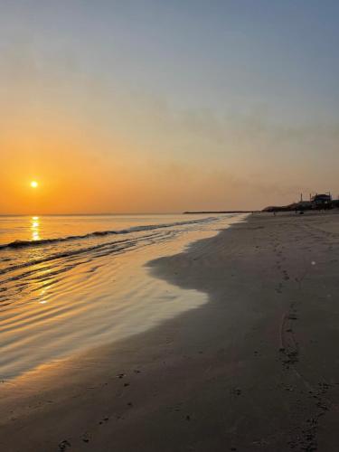 ein Strand, an dem die Sonne über dem Wasser untergeht in der Unterkunft Residence BASI - Appartement 2 chambres in Rufisque