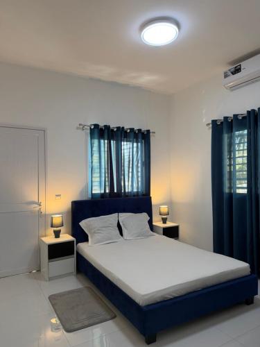 a bedroom with a large bed with blue curtains at C-Appart Residence in Tuléar
