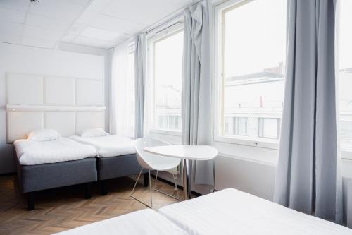 a room with two beds and a table and windows at Omena Hotel Helsinki Lönnrotinkatu in Helsinki