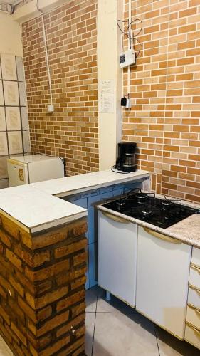 a kitchen with a stove and a brick wall at Casa63 in Lençóis