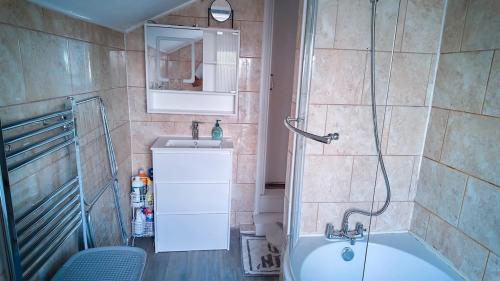 a bathroom with a shower and a tub and a sink at Luxurious Modern Town House in Gillingham