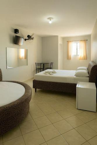 a bedroom with two beds and a table and chairs at Londres hotel thur in Brasília