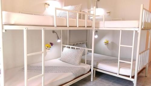 a room with two bunk beds with white furniture at Salsa Hostel in Chumphon