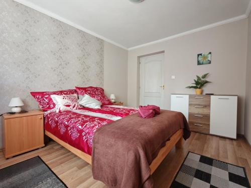 a bedroom with a red bed and a dresser at Katalin Apartmanház in Miskolctapolca