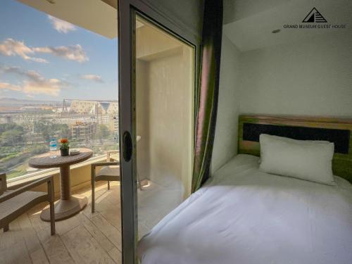 a bedroom with a bed and a balcony with a table at Grand Museum with Pyramids view inn in Cairo