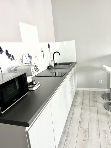 a white kitchen with a sink and a microwave at City Centre Balcony Apartments in Wadowice