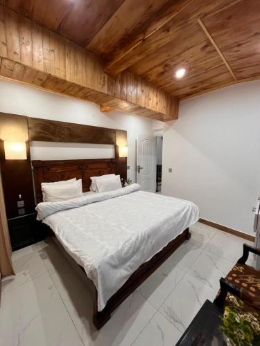 a bedroom with a large white bed with wooden ceilings at Pine Cottage in Murree
