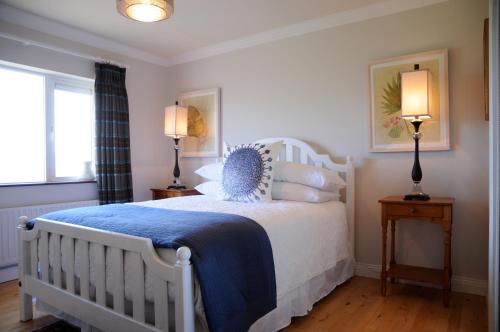 ein Schlafzimmer mit einem weißen Bett mit einer blauen Decke in der Unterkunft Short Strand Dingle in Dingle