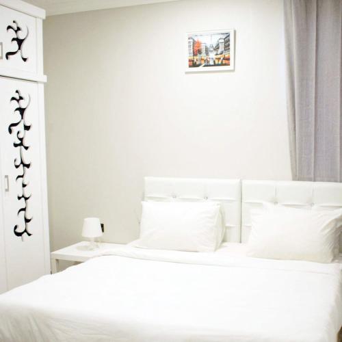a white bedroom with a white bed with white pillows at Leader Hotels Salmiya in Kuwait