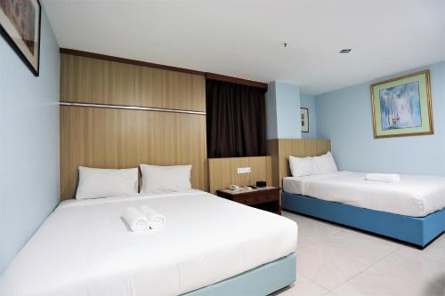 a hotel room with two beds with white sheets at Hotel La ISRA at Kuala Lumpur in Kuala Lumpur
