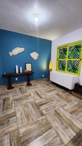 a living room with a blue wall and a wooden floor at Casa com piscina e próxima ao mar em Imbe in Imbé