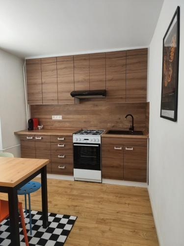 a kitchen with wooden cabinets and a stove and a table at Studio11 in Medzilaborce