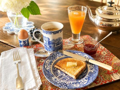 a table with a plate of toast and a glass of orange juice at Bailey House Inn - Georgian Waterfront Retreat in Annapolis Royal