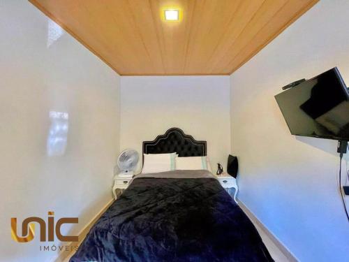 a bedroom with a bed and a flat screen tv at Loft em Teresópolis in Teresópolis
