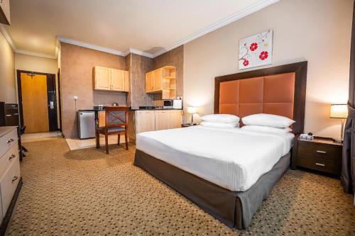 a bedroom with a large bed and a kitchen at Kingsgate Hotel Doha by Millennium Hotels in Doha