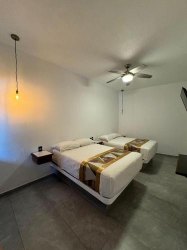 two beds in a room with a ceiling fan at Hotel Boutique Manta in Los Ayala