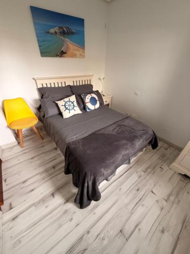 a bedroom with a large bed and a yellow chair at El Pinar de Mogro in Mogro