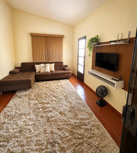 a living room with a couch and a flat screen tv at Casa Spring in Alfenas