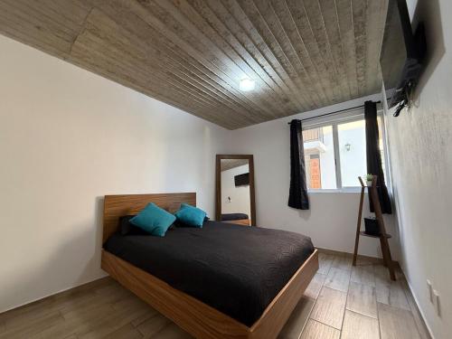 a bedroom with a bed with blue pillows on it at Lovely chalet in Mazamitla in Puente de las Cuevas