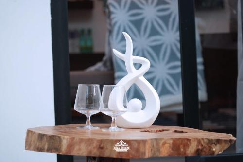 two wine glasses and a statue on a wooden table at Geza Breeze Residence in Dar es Salaam