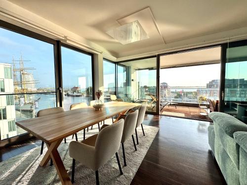 a dining room with a table and chairs and windows at Bheaven I Captains Apartment in Bremerhaven