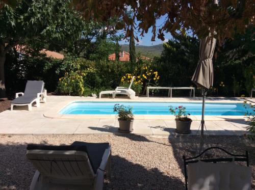 - une piscine avec 2 chaises et un parasol dans l'établissement Gite De La Sueur Au Bonheur, à La Bouilladisse