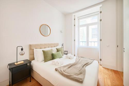 a white bedroom with a large bed and a mirror at Casa Portuguesa Ouro in Lisbon