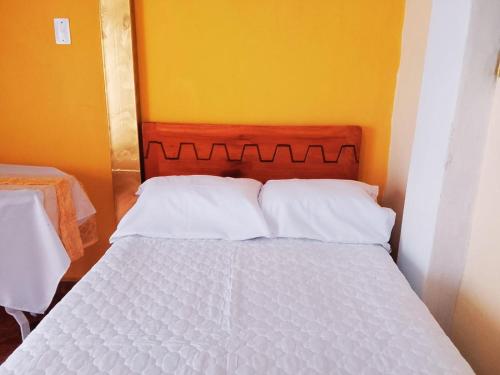 a bed with white pillows in a room with a yellow wall at 1 BR Room 1 floor Cusco in Cusco