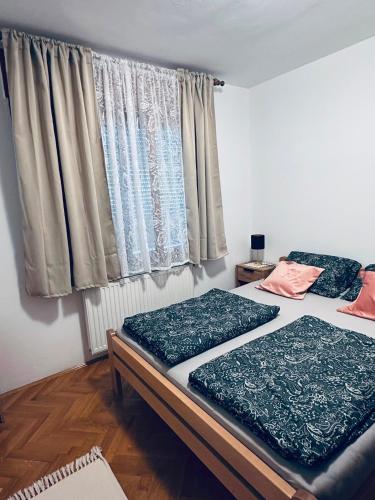 two beds in a room with a window at Kuća za odmor MEDUNIĆ in Gospić