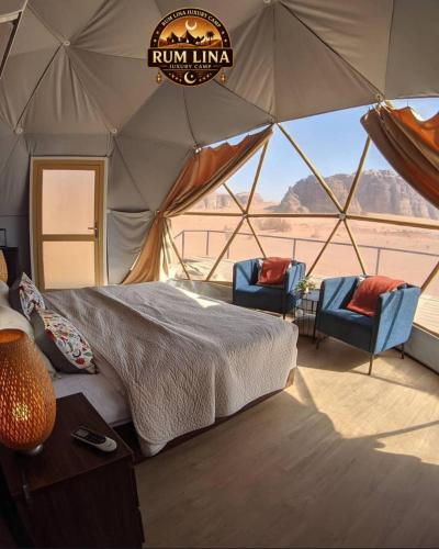 a bedroom with a bed and two chairs in a tent at RUM LlNA lUXRY CAMP in Wadi Rum