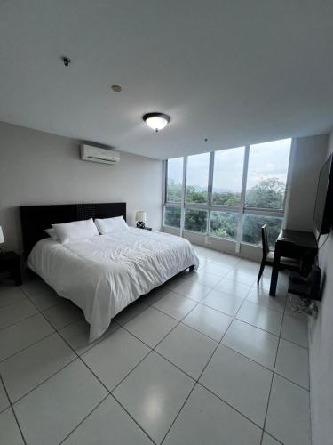 a white bedroom with a bed and a desk and window at Beach apartment on the seashore in Las Lajas