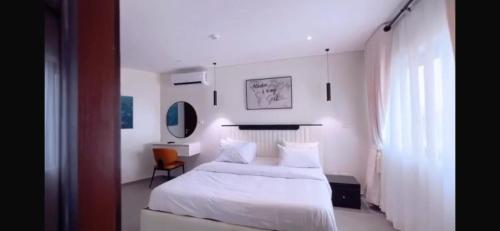 a white bedroom with a bed and a chair at Orange Place - Benson Close in Lagos
