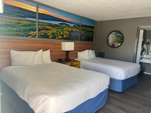 a hotel room with two beds and a painting on the wall at Days Inn & Suites by Wyndham Needles in Needles
