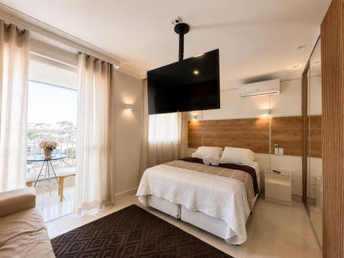 a bedroom with a bed and a flat screen tv at Luxury Studio - Próx Aeroporto GRU - Com Ar Condicionado in Guarulhos