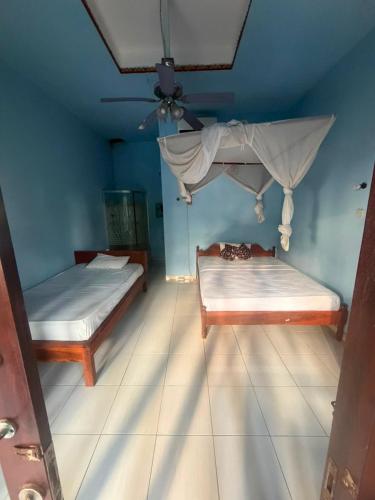 two beds in a room with a ceiling fan at Amed beach homestay in Ambat