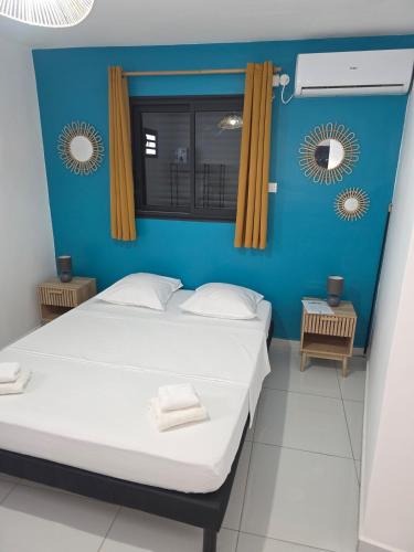 a bedroom with two beds and a blue wall at Bas de villa in Grand-Bourg