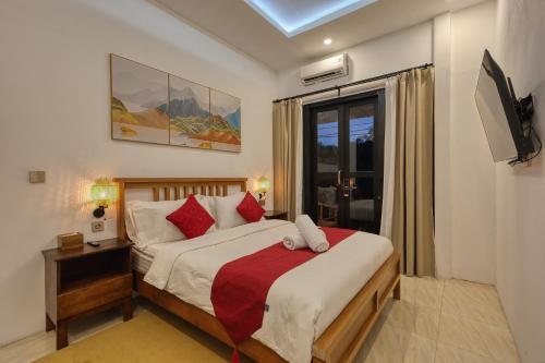 a bedroom with a bed with red pillows and a window at Villa Astella in Nusa Penida