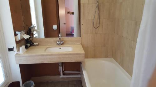 a bathroom with a sink and a bath tub at Hôtel Média in Paris