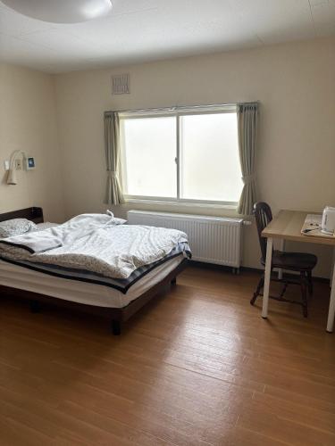 a bedroom with a bed and a window and a desk at Guesthouse Yoichi in Yoichi