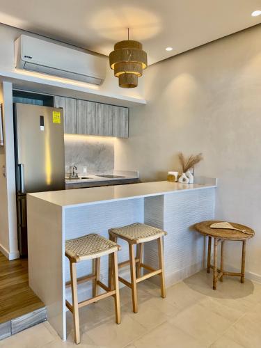 a kitchen with a counter with stools and a sink at Suite Deluxe frente al Mar - Playa & GYM in Acapulco