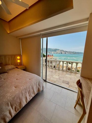 a bedroom with a bed and a view of the beach at Suite Deluxe frente al Mar - Playa & GYM in Acapulco