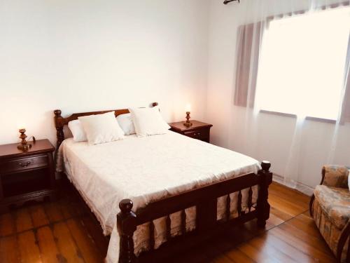 a bedroom with a bed and a couch and a window at Casa de Cima in Doze Ribeiras