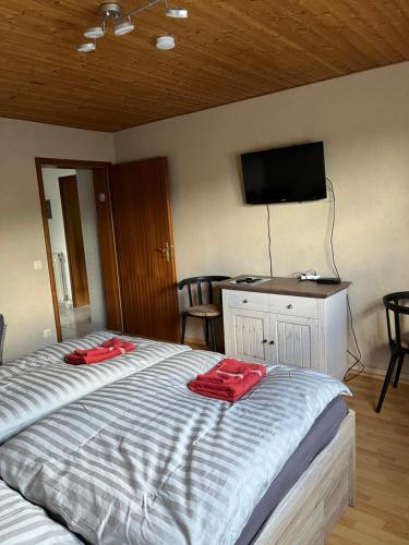 a bedroom with a bed with two red towels on it at Ferienwohnung am Rande des Rothaarsteigs in Kreuztal