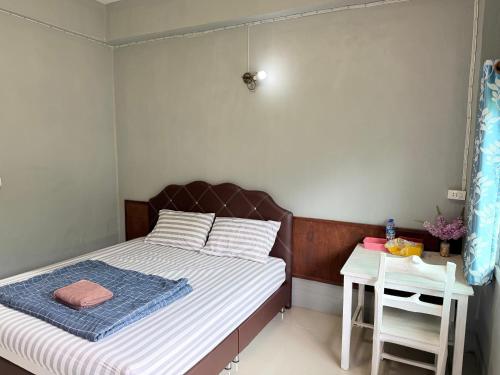 a small bedroom with a bed and a table at boomhousehotel in Chiang Khong