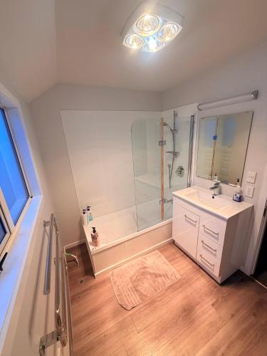 a white bathroom with a shower and a sink at Cozy Escape in Wanaka